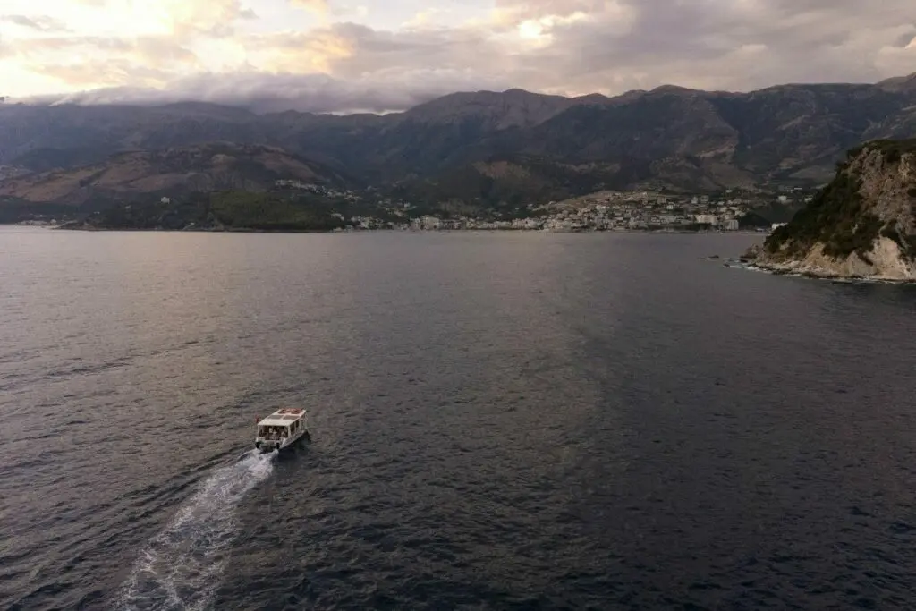 Baia di Himara al crepuscolo, con una barca e la cittadina sulla riva