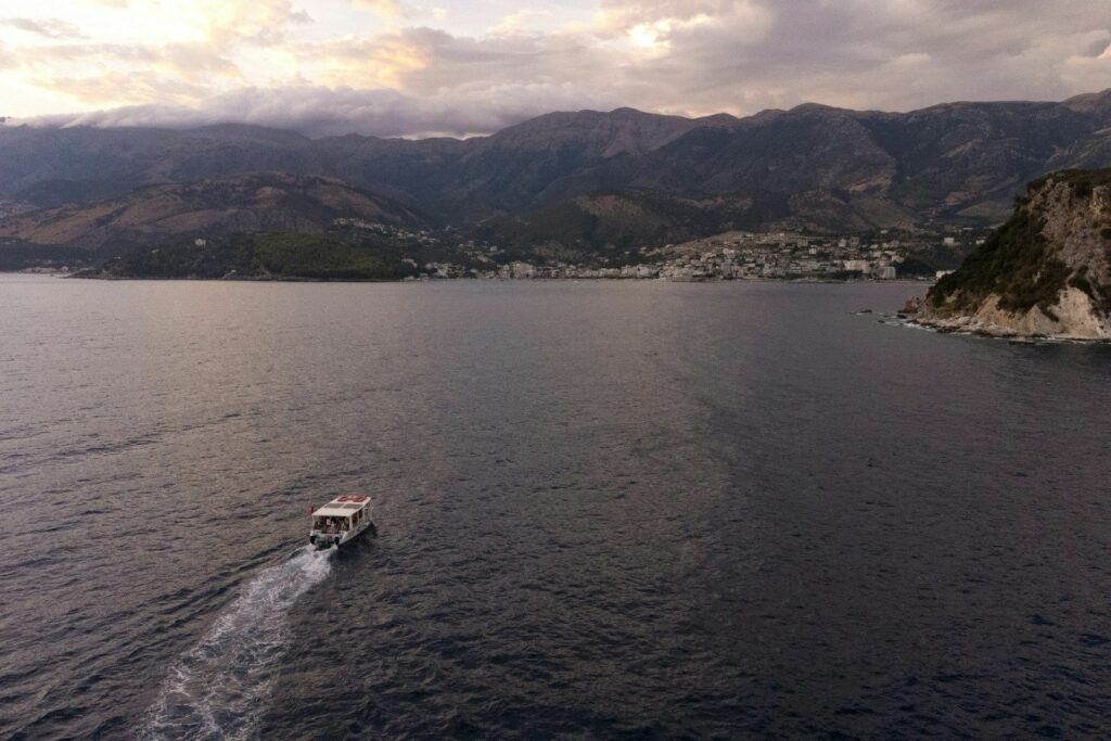 Gjiri i Himarës në muzg, me një varkë dhe qytetin në breg