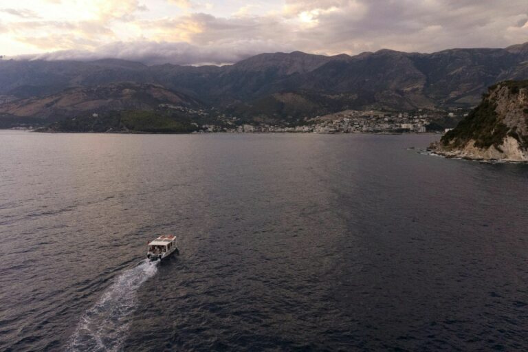 Gjiri i Himarës në muzg, me një varkë dhe qytetin në breg
